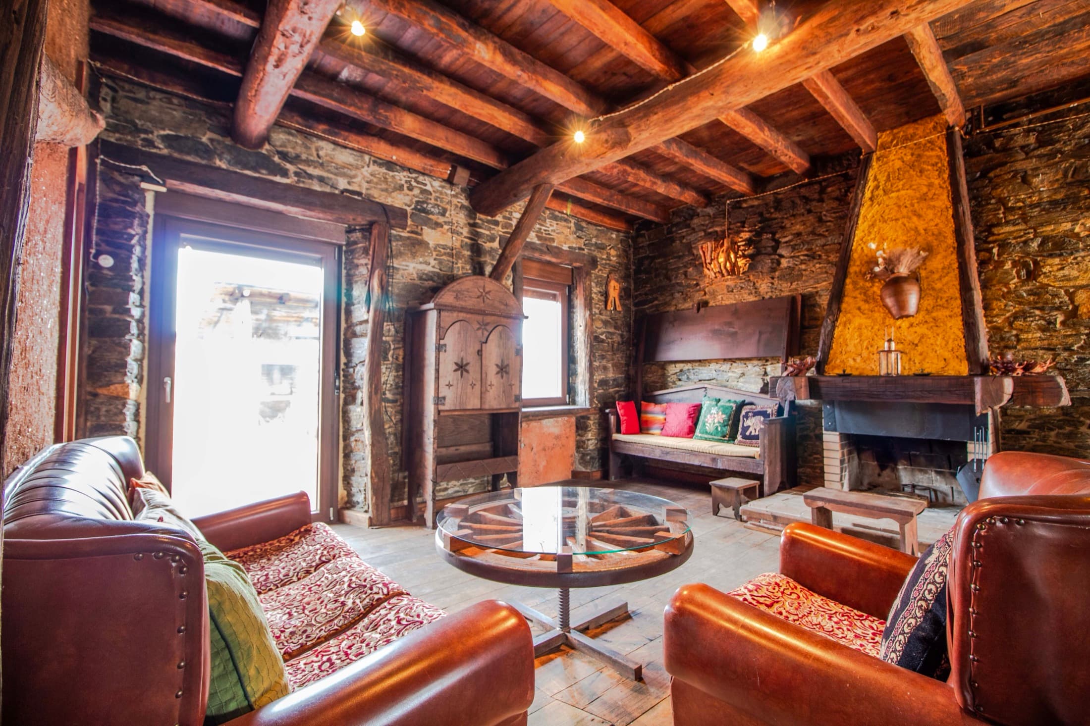 Salón de piedra con chimenea y sofás de cuero